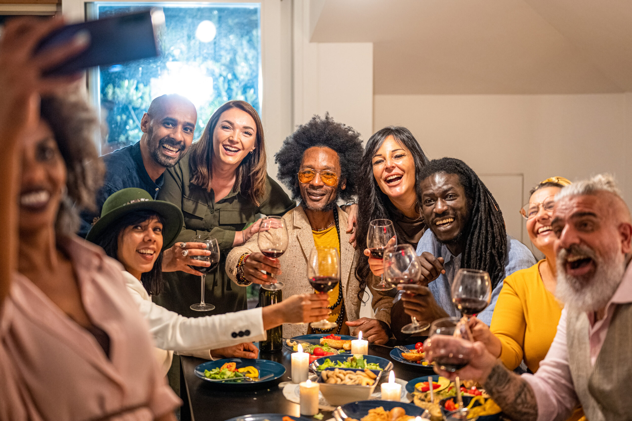 A diverse group of LGBTQIA+ friends sharing a meal together, laughing and embracing, representing chosen family bonds in the queer community