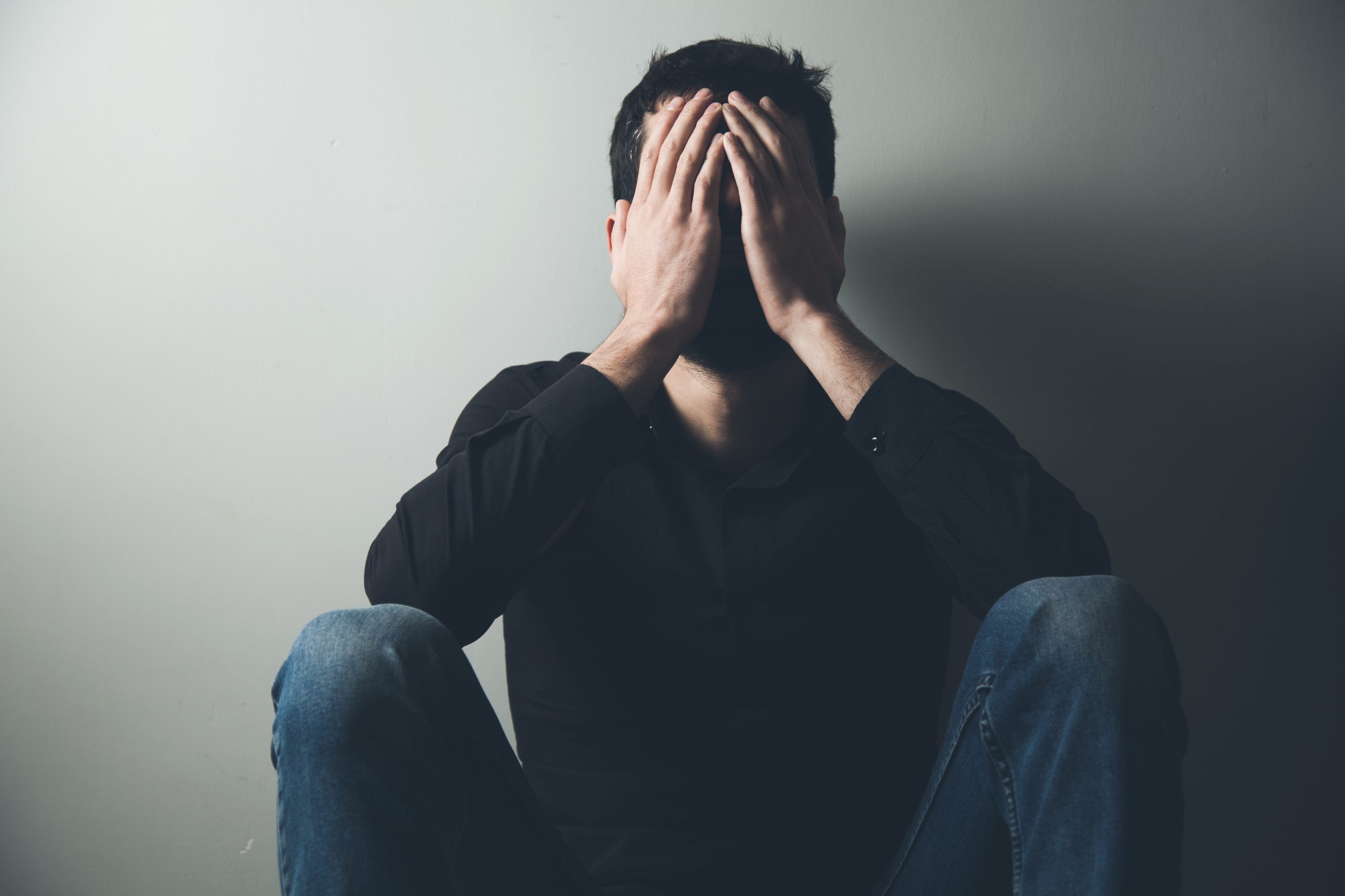 Person sitting on the floor with their face covered by their hands, conveying emotional distress, shame, grief, or overwhelm following a relationship crisis.