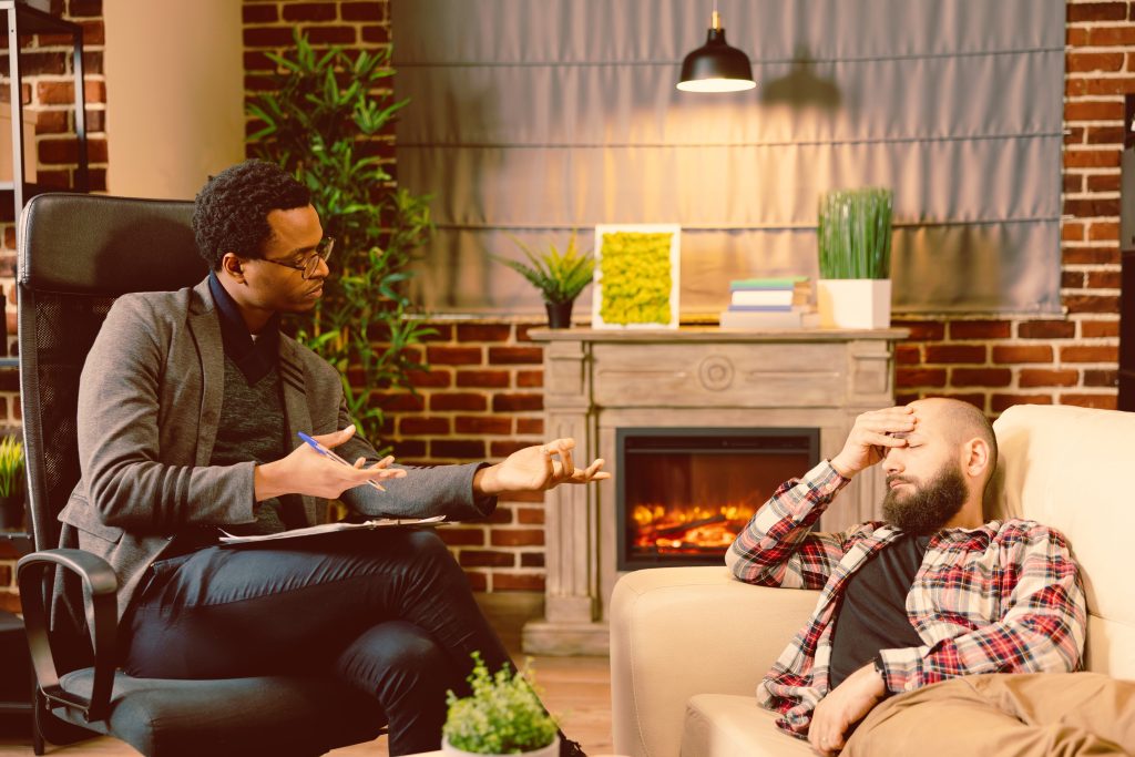 Therapist speaking with a client who appears overwhelmed by stress, anxiety, or emotional exhaustion during a counseling session.