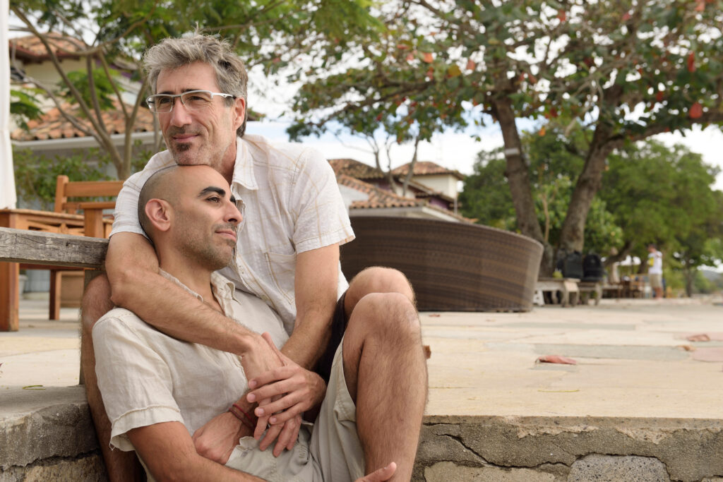 Older male couple sharing a quiet, affectionate moment outdoors